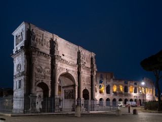 Vista nocturna del Coliseo con el arco de Constantino en el primer plano