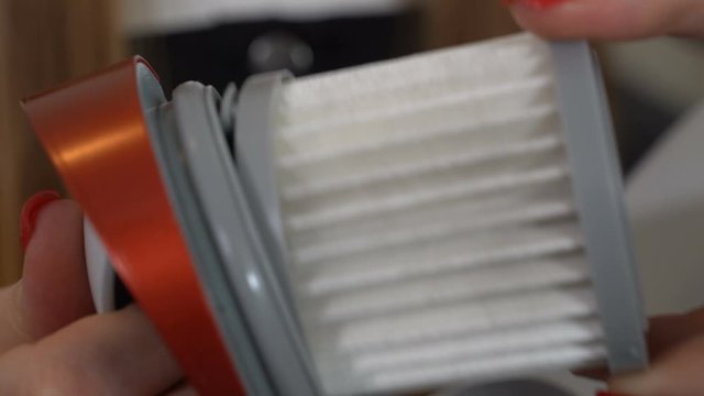 The girl takes out the filter from the vacuum cleaner on the battery