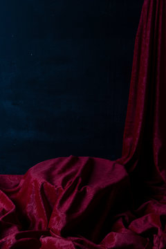 Tela Roja que cae sobre un plato circular como para poner un postre. Fondo negro. Escena teatral para montaje digital