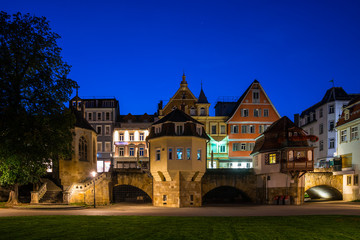 Fototapeta na wymiar Germany, Beautiful colorful old illuminated houses in medieval old town of esslingen am neckar behind green meadow by night in magical twilight atmosphere after sunset in summer with starry sky