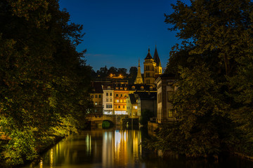 Germany, Beautiful ancient illuminated houses of medieval historic district of esslingen am neckar reflecting in water by night with starry sky in summer twilight atmosphere