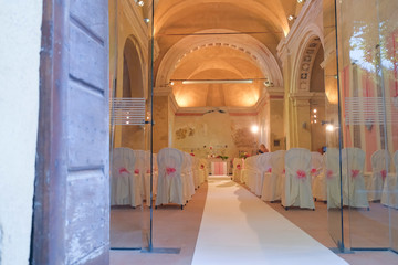 interno di chiesa addobbata con fiori e sedie bianche