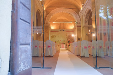interno di chiesa addobbata con fiori e sedie bianche