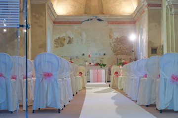 interno di chiesa addobbata con fiori e sedie bianche