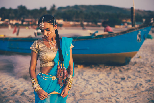 a girl dressed in indian saree near the fisherman's boat