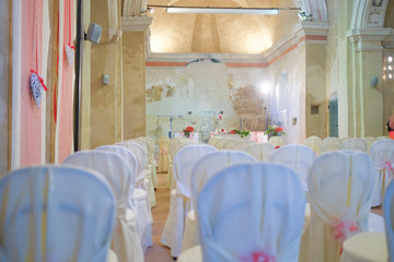 interno di chiesa addobbata con fiori e sedie bianche