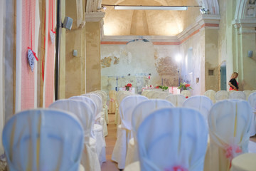 interno di chiesa addobbata con fiori e sedie bianche