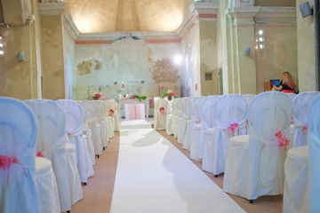 interno di chiesa addobbata con fiori e sedie bianche