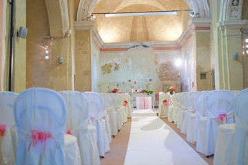 interno di chiesa addobbata con fiori e sedie bianche