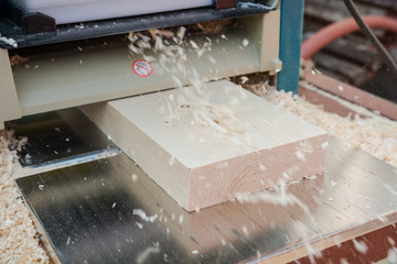 planing boards on a thicknesser. wood shavings. machine for planing wood. carpentry work. joiner's machine.