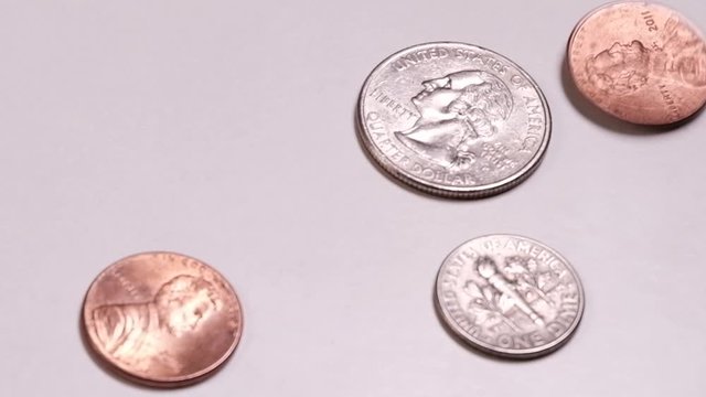 Small American coins spin on the table. A quarter dollar, one dime and two cents on a white background. Theme of banking and financial crisis or wealth accumulation.