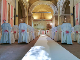 interno di chiesa addobbata con fiori e sedie bianche