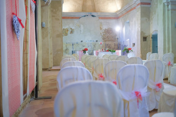 interno di chiesa addobbata con fiori e sedie bianche