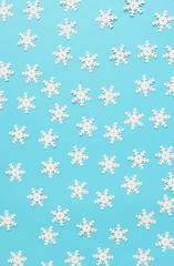 White snowflakes confetti pattern on blue color background. Minimal  holiday concept. Winter festive backdrop. Top view, flat lay