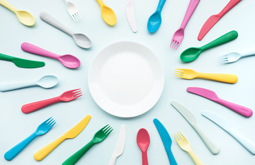 Top view of dish with colorful spoon and fork element on color table.