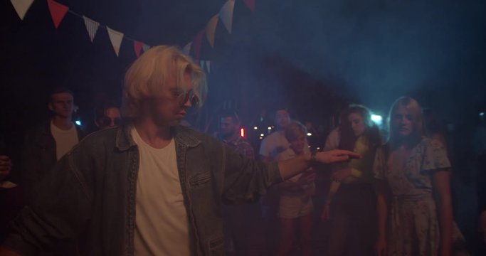 Attractive young man with multi-ethnic people dance party in different clothes drinking alcohol having fun on weekend laughing sharing socializing celebration close up slow motion