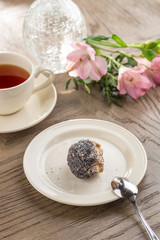 Homemade vegan Raw Energy Balls with honey, poppy seeds and coconut and cup of tea on wooden table