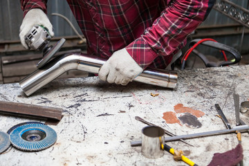 Surface preparation of stainless steel pipes using an angle grinder for further welding in an iron workshop. Industry and production.