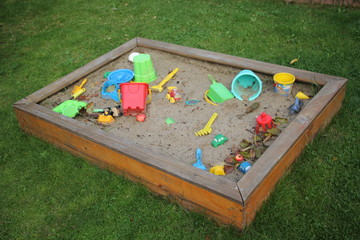 children's sandbox with toys on green grass