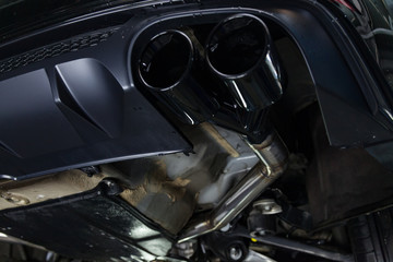 Bottom view of the car on a bifurcated exhaust system, rear bumper with a sports diffuser and nozzles in black. Tuning and atom service industry. - obrazy, fototapety, plakaty
