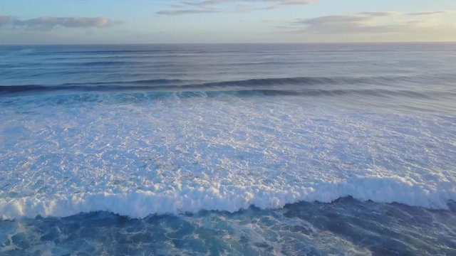 Drone aerial reveal of beach with big waves at sunrise
