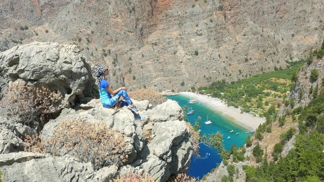 Young woman enjoying freedom and taking sun bath with beatiful viewn of Butterfly Valley on background in Turkey