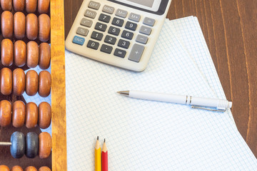 Vintage abacus, sheets of paper, calculator, two pencils and pen. Copy space