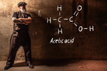 Bearded old man presenting handdrawn chemical formula of Acetic acid CH3COOH