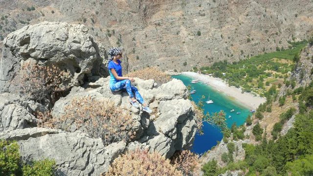 Young woman enjoying freedom and taking sun bath with beatiful viewn of Butterfly Valley on background in Turkey