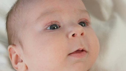 Portrait of beautiful funny little newborn baby of two months lying on a white bed