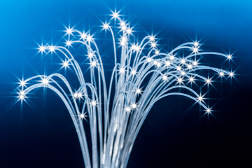 Bundle of optical fibers with lights in the ends. Blue background.