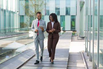 Happy businessman showing content on tablet to female colleague. Business man and woman walking...