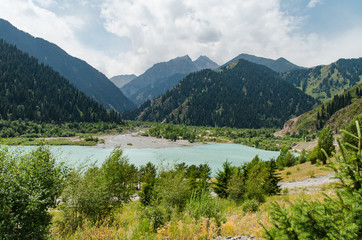 A blue lake among high mountains, on the slopes of which grow green spruce and other trees