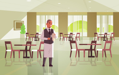 Fototapeta premium professional waiter polishing wine glass with towel man restaurant worker in uniform modern cafe interior flat full length horizontal