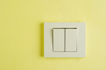 Electric switch with space for text on yellow wall.