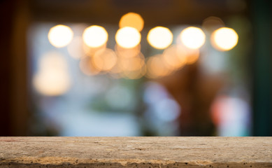 Empty wood table top on blur light gold bokeh of cafe restaurant in dark background