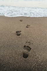 Fototapeta na wymiar Deep footprints in sand leading to water