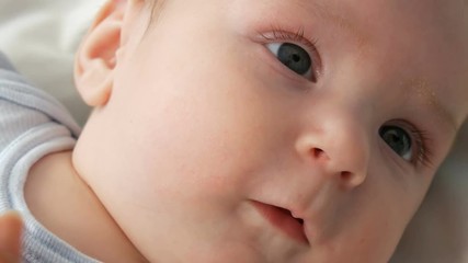 Portrait of beautiful funny little newborn baby of two months lying on a white bed