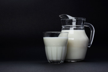 Jar and glass of milk isolated on black background with copy space for text, dairy product concept