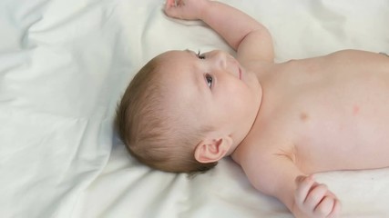 Portrait of beautiful funny little newborn baby of two months lying on a white bed