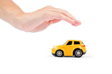 Car insurance. Car miniature covered by hands.