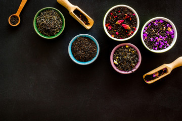 Assortment of dry tea in bowls frame on black background top view copyspace