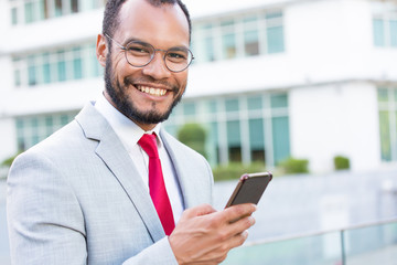 Happy joyful businessman with smartphones posing outdoors. Young Latin business man holding mobile phone and smiling at camera. Digital technology concept