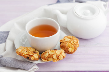 Cup of tea with cookies over lilac wooden background