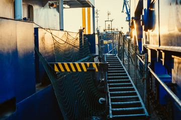 Stern of cargo vessel at port. Gangway arrangment. Blue hull.