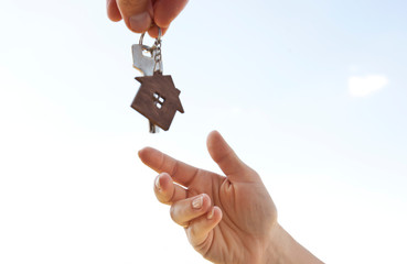 Man giving the metal key from door with wooden trinket in shape of house to the woman