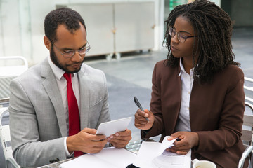Business colleagues studying reports during coffee break. Business man and woman sitting in cafe,...