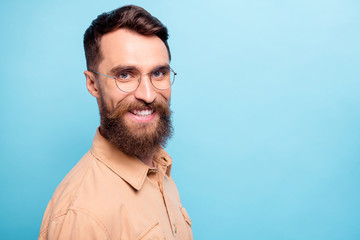 Turned photo of charming man looking with beaming smile wearing brown shirt isolated over blue background