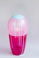 Pink balloon in flowerpot with blue dripping paint on grey background