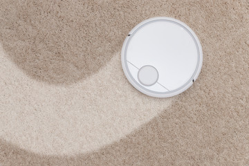 Fototapeta na wymiar Robotic wireless smart vacuum cleaner working on white with pile carpet
